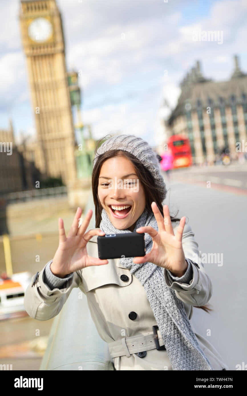 Travel tourist in london sightseeing taking selfie photo pictures near Big Ben. Woman holding smart phone camera smiling happy near Palace of Westminster, Westminster Bridge, London, England Stock Photo