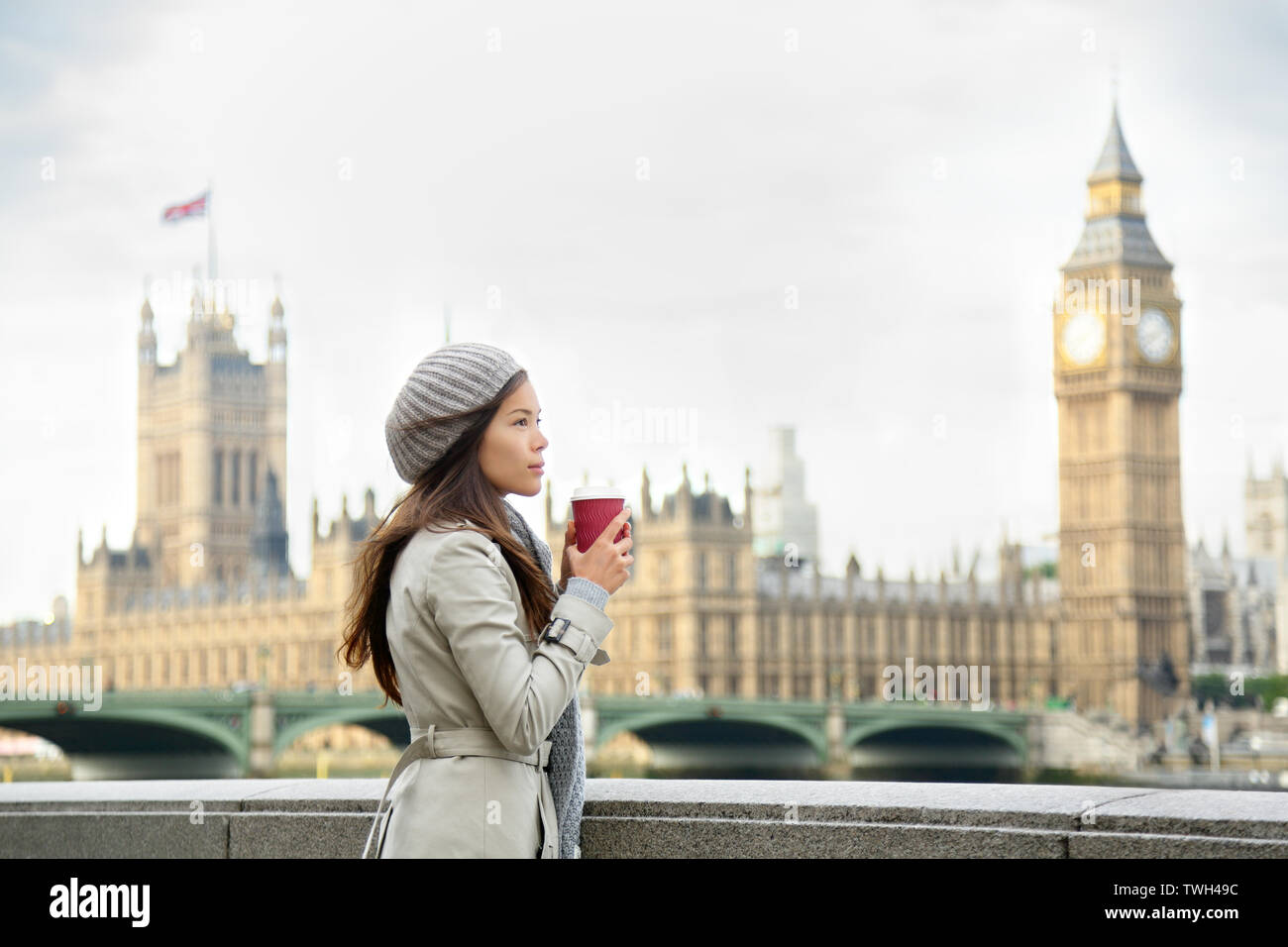 London woman drinking coffee by Westminster Bridge. Serious pensive thoughtful young female professional business woman in London, England. Beautiful young multiracial Asian Caucasian girl. Stock Photo