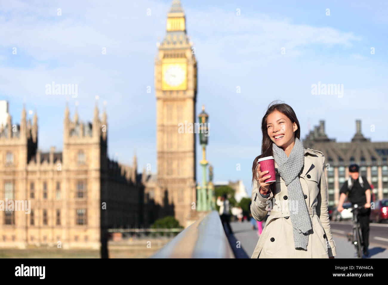London woman happy by Big Ben laughing and drinking coffee in autumn. Young female professional on Westminster Bridge, London, England. Beautiful young multiracial Asian Caucasian girl. Stock Photo