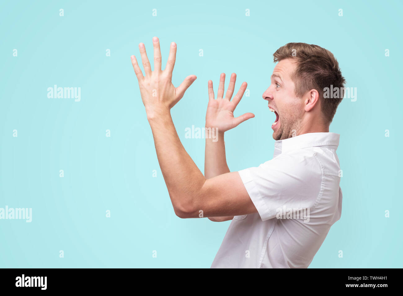 Young man screaming aside with hands gesture isolated on blue background Stock Photo