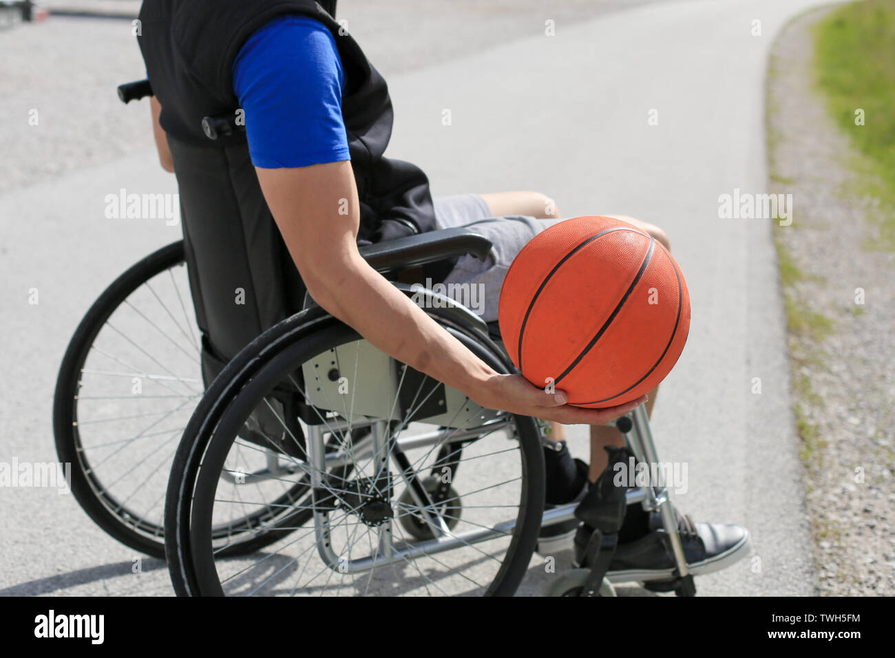 Disabled young basketball player on a wheelchair holding ball and