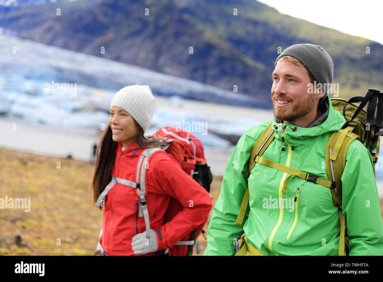 Hiking adventure travel people living active healthy lifestyle wearing jackets and backpacks on Iceland by glacier and glacial lagoon / lake of Fjallsarlon, Vatna glacier, Vatnajokull National Park. Stock Photo