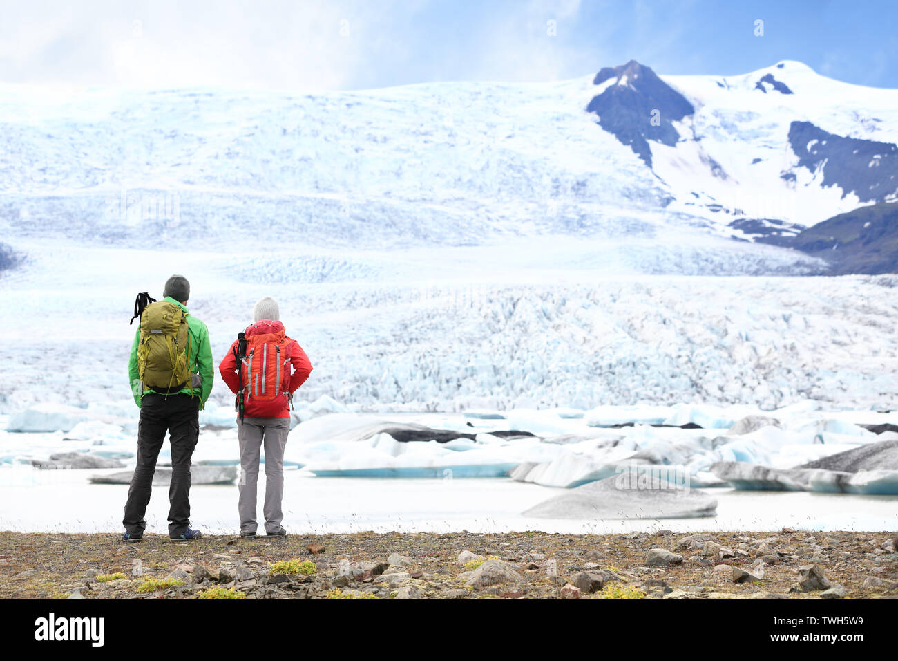 Hiking adventure travel people on Iceland. Hikers looking at glacier and glacial lagoon / lake of Fjallsarlon, Vatna glacier, Vatnajokull National Park. Couple visiting Icelandic nature landscape. Stock Photo