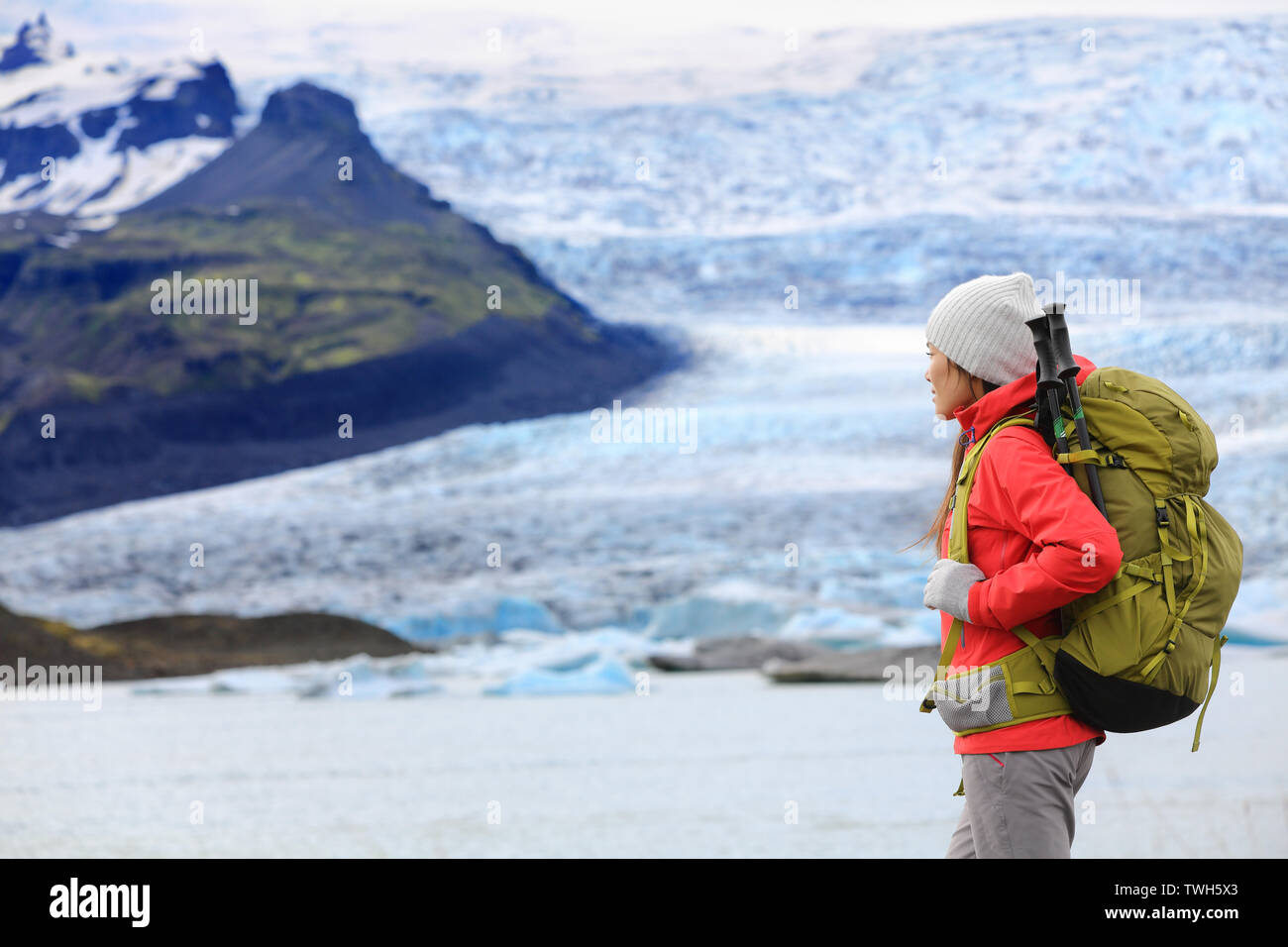 Adventure hiking woman by glacier on Iceland. Hiker trekking walking by glacial lagoon / lake of Fjallsarlon, Vatna glacier, Vatnajokull National Park. Young woman visiting Icelandic nature landscape. Stock Photo
