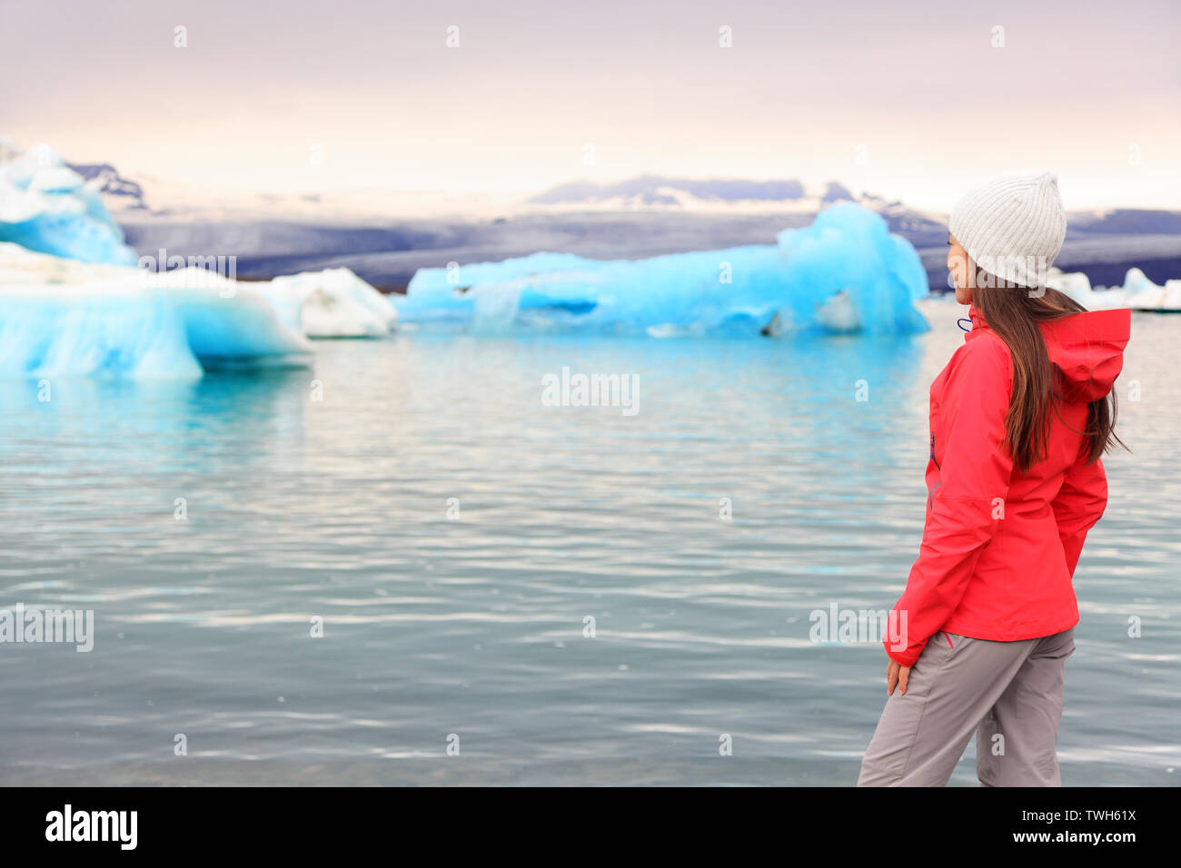 Iceland glacial lagoon. Woman looking at view of Icelandic glacier lake Jokulsarlon. Beautiful young multiracial woman living outdoors lifestyle looking at icebergs. Stock Photo