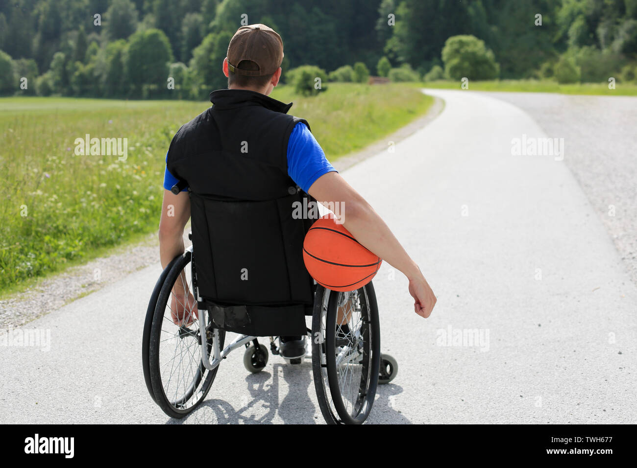 Disabled young basketball player on a wheelchair holding ball and beeing active in sport Stock Photo