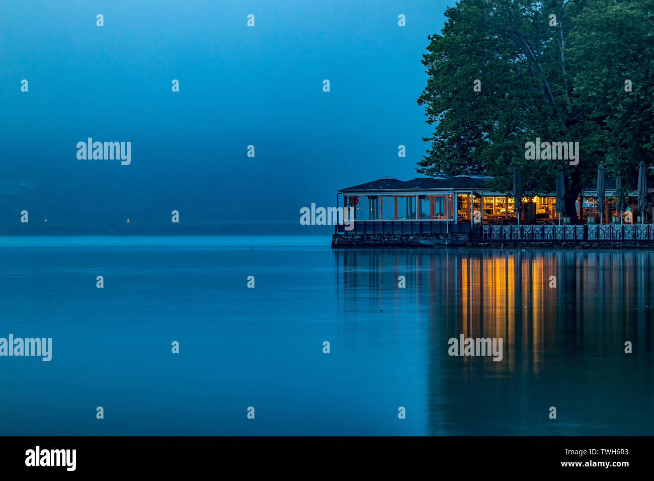 Ioannina, Greece, lake misty early spring morning with fog over the lake Pamvotida calm waters. Light reflections, high contrast mystical picture, long exposure photograph Stock Photo