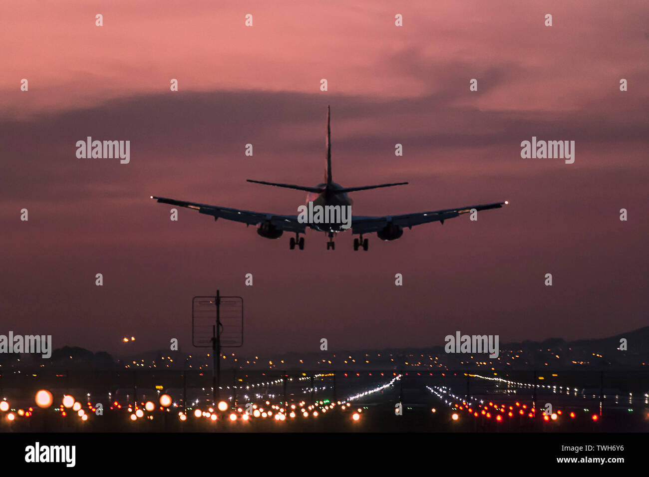 Passenger aircraft landing at the Cape Town International Airport at dusk with the landing strip clearly lit up. Stock Photo
