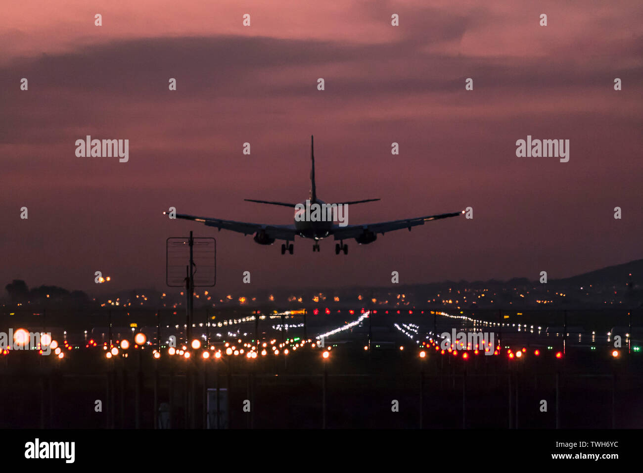 Passenger aircraft landing at the Cape Town International Airport at dusk with the landing strip clearly lit up. Stock Photo