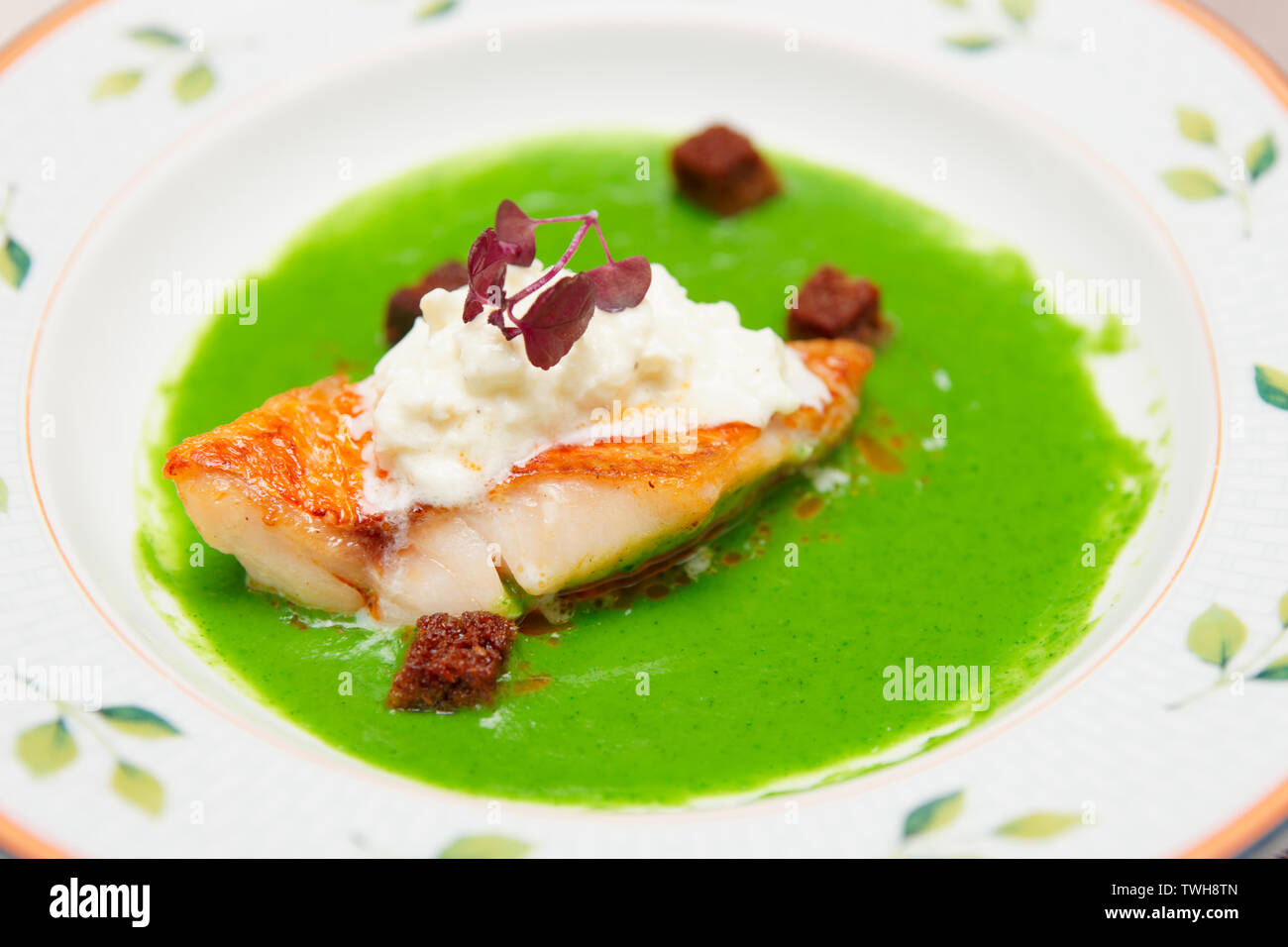 Seabass with herbs and spinach puree in plate, close-up Stock Photo