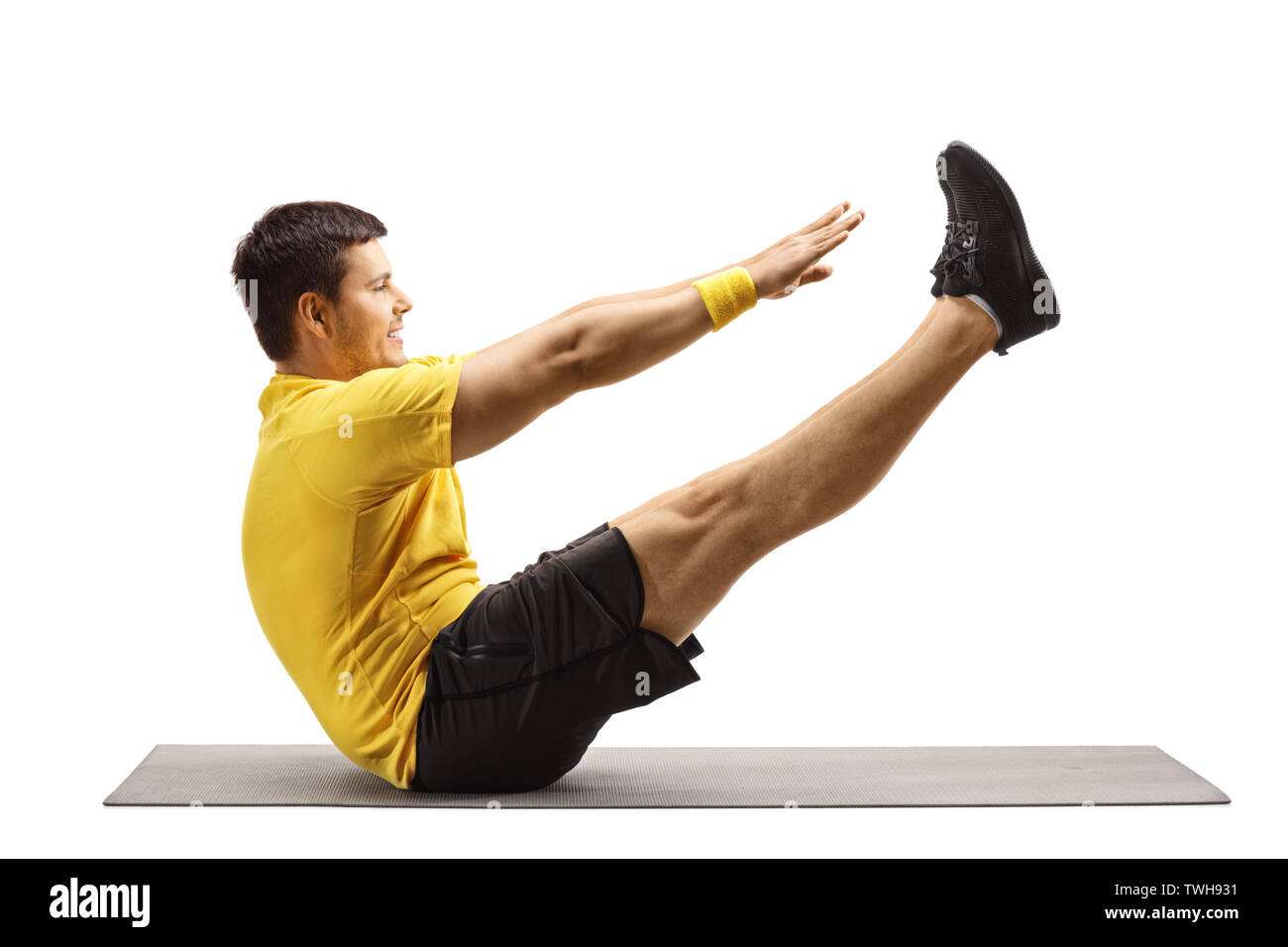 Full length profile shot of a young man stretching on an exercise mat isolated on white background Stock Photo