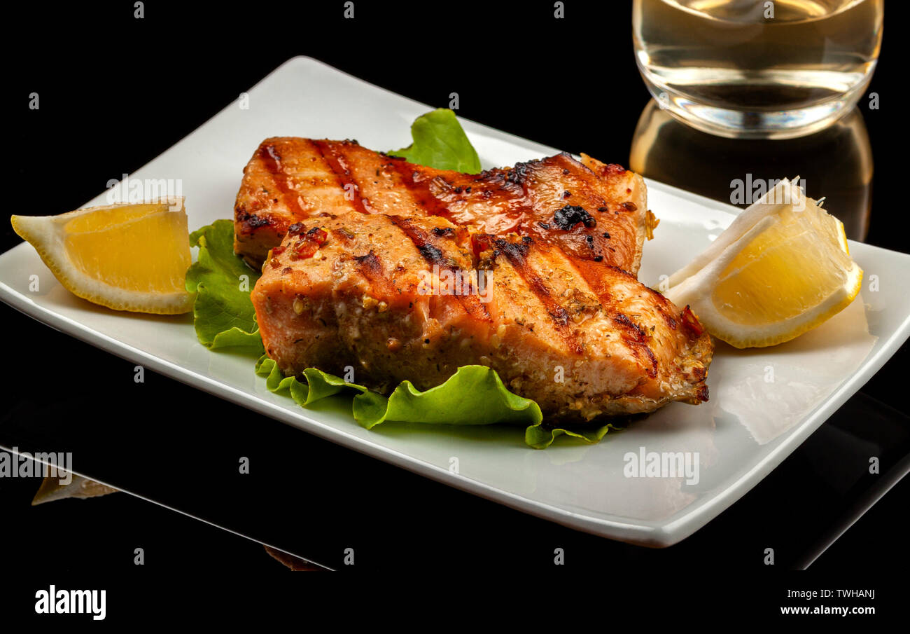 Fish, trout, chum salmon, humpback, a piece baked, grilled, with a slice of lemon and lettuce Stock Photo