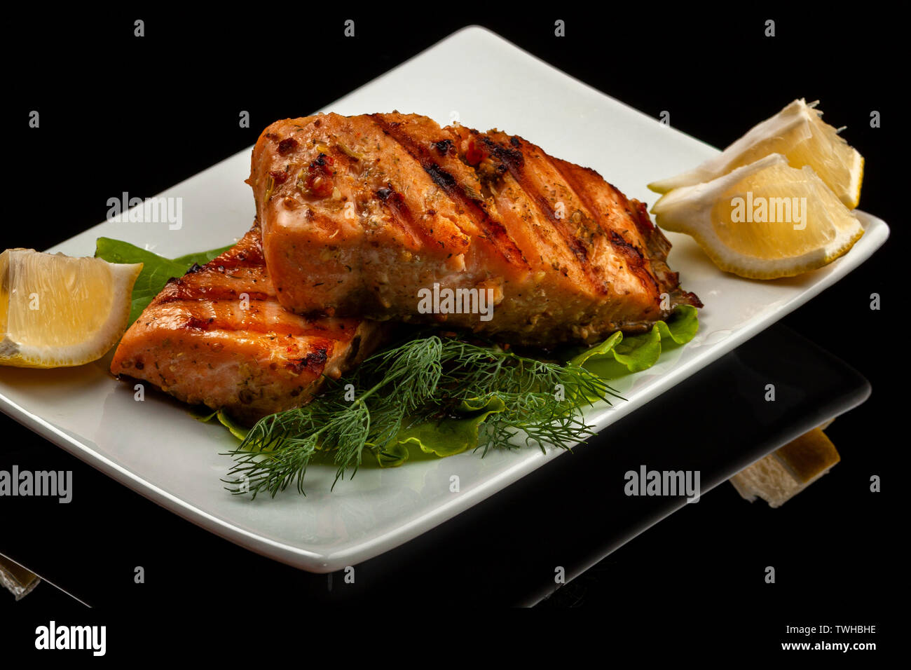 Fish, trout, chum salmon, humpback, a piece baked, grilled, with a slice of lemon and lettuce Stock Photo
