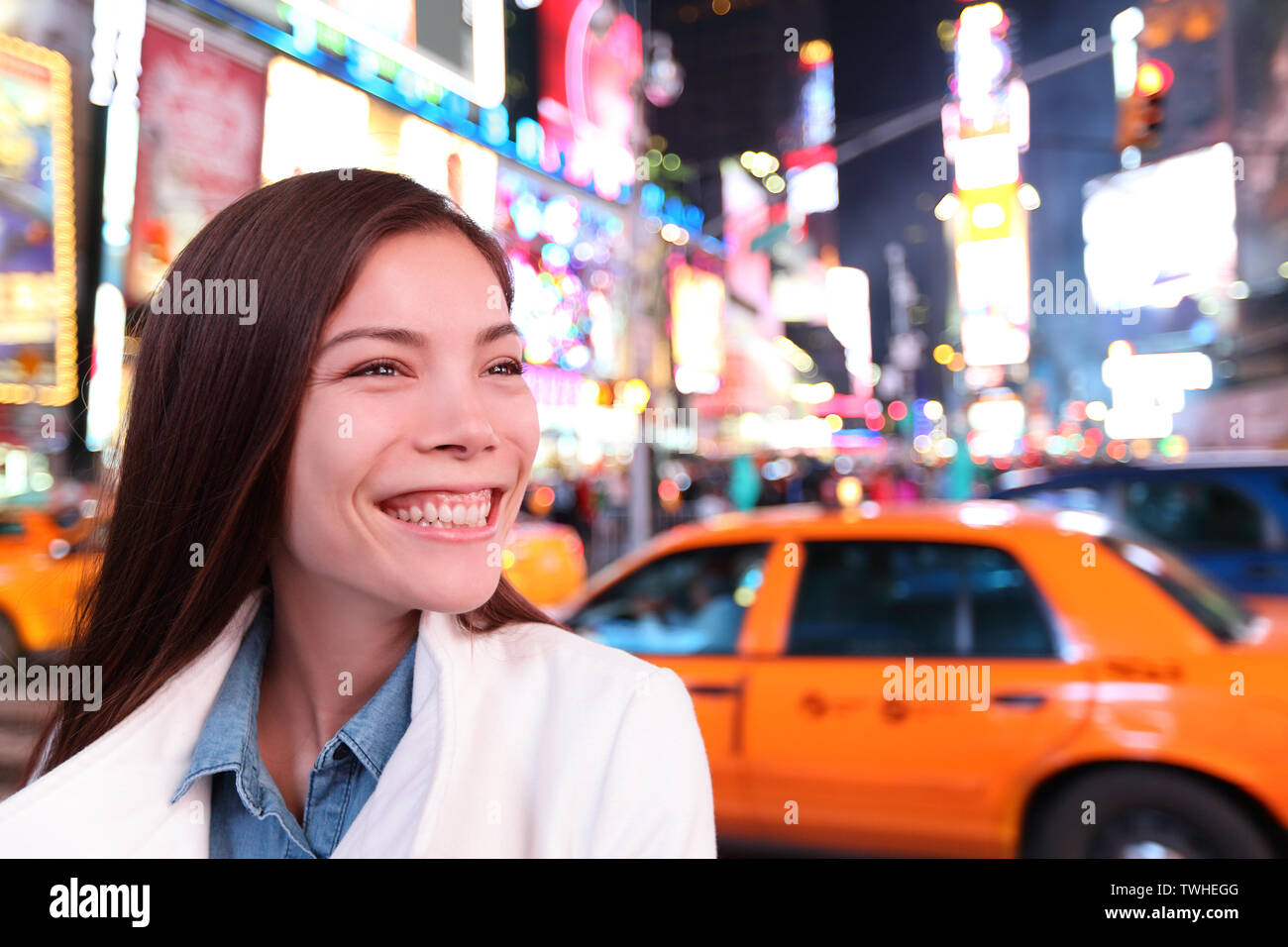 Woman in New York City, Manhattan, Times Square at night. Smiling happy