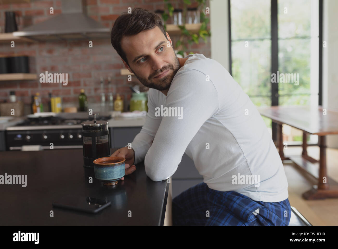Man with coffee cup looking away at dining table Stock Photo