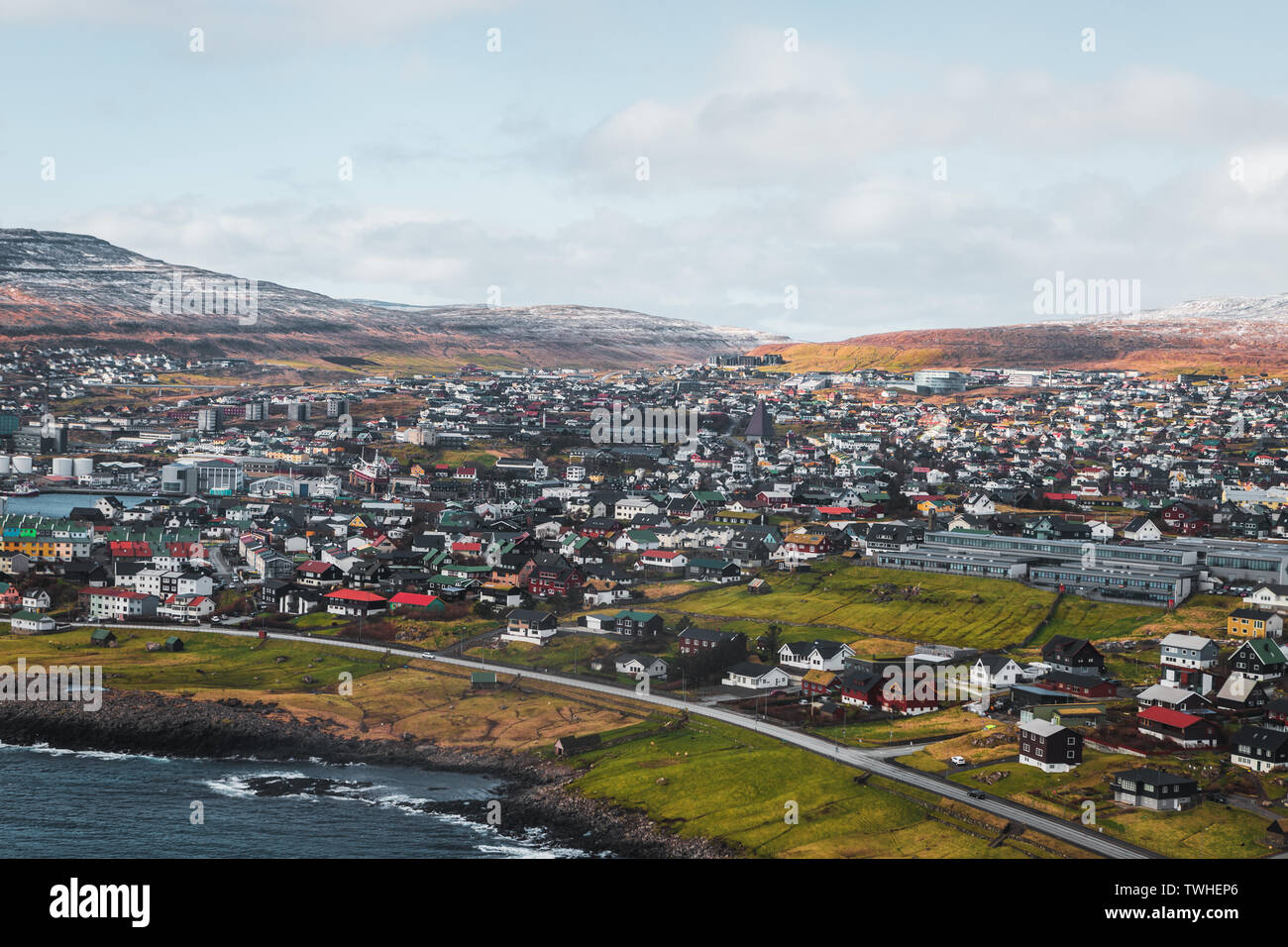 Aerial shot of the town Torshavn as taken during a helicopter flight on an early spring morning with snow-covered mountains (Faroe Islands, Denmark) Stock Photo