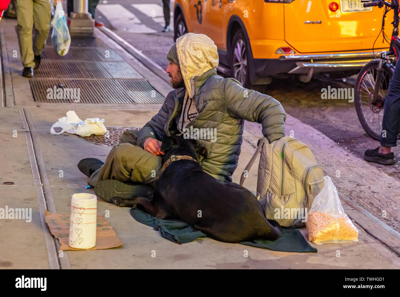USA, New York. May 3, 2019. Homeless man and a dog sitting on the sidewalk, asking for help, Manhattan downtown Stock Photo
