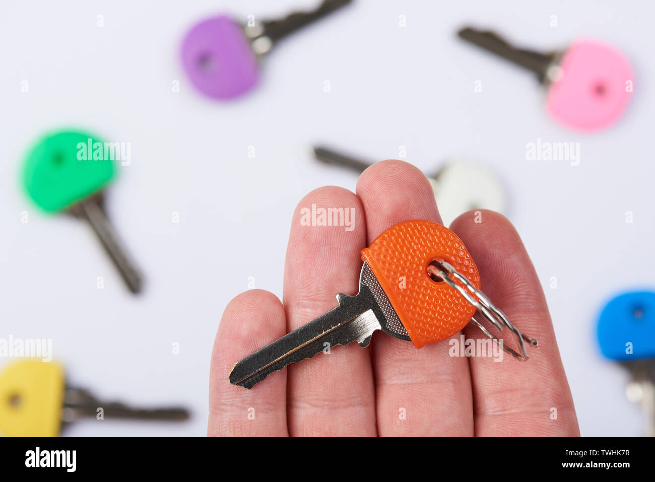 Orange lock key on human palm hand with blurred keys background Stock Photo