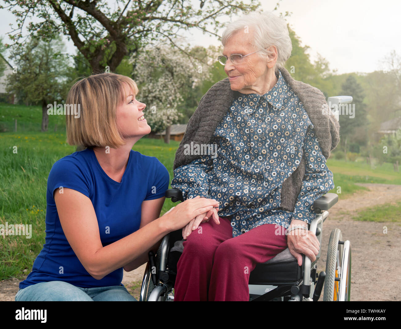 Young woman smiling at senior sitting in wheelchair Stock Photo