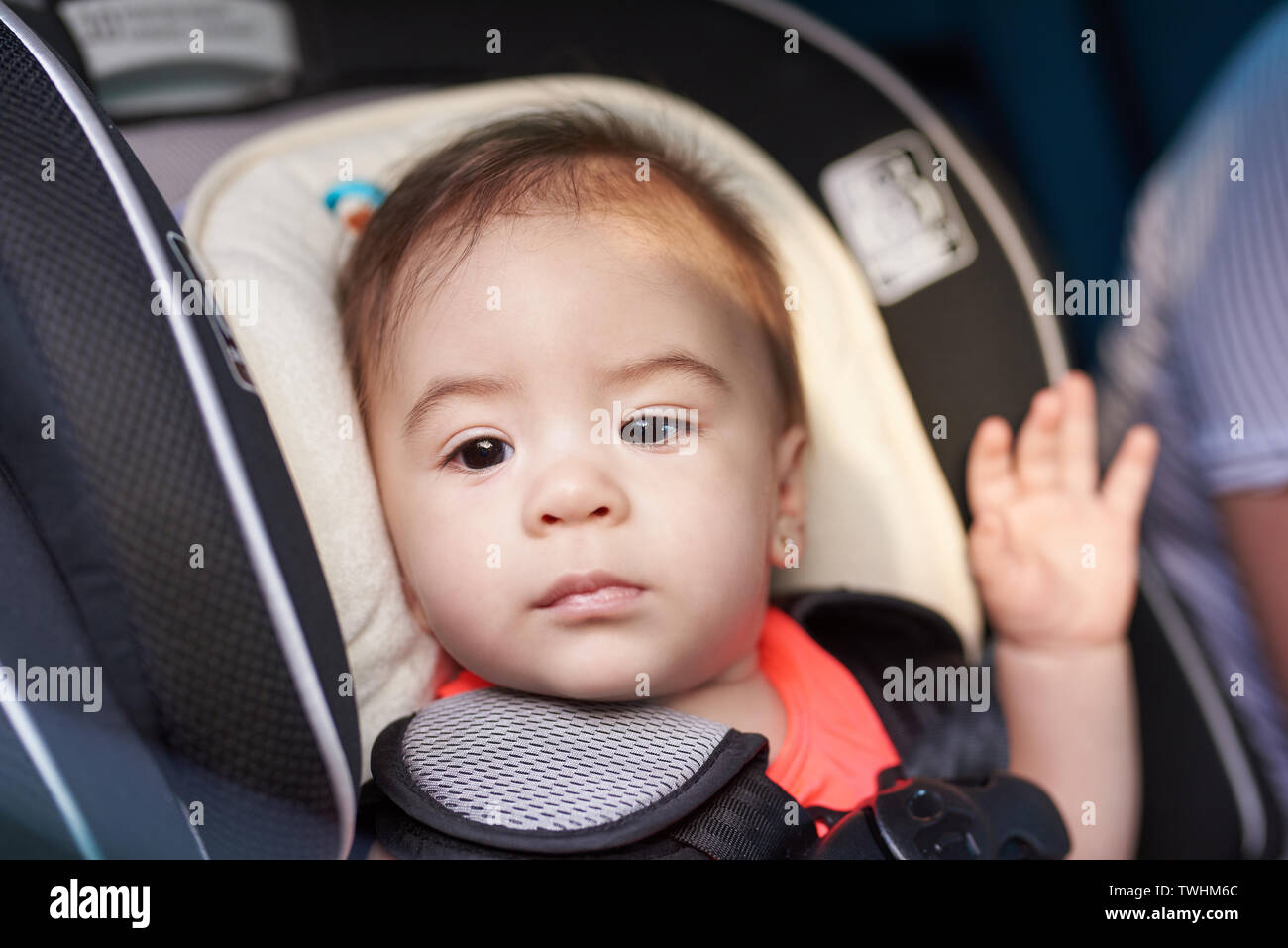 Portrait of small baby girl looking in window in car seat Stock Photo
