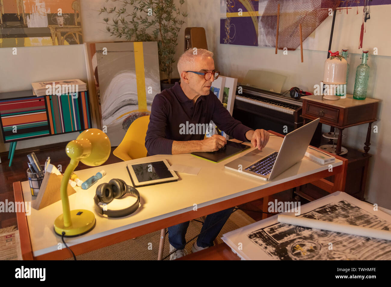Middle aged man using computer in his art studio and drawing on his tablet Stock Photo