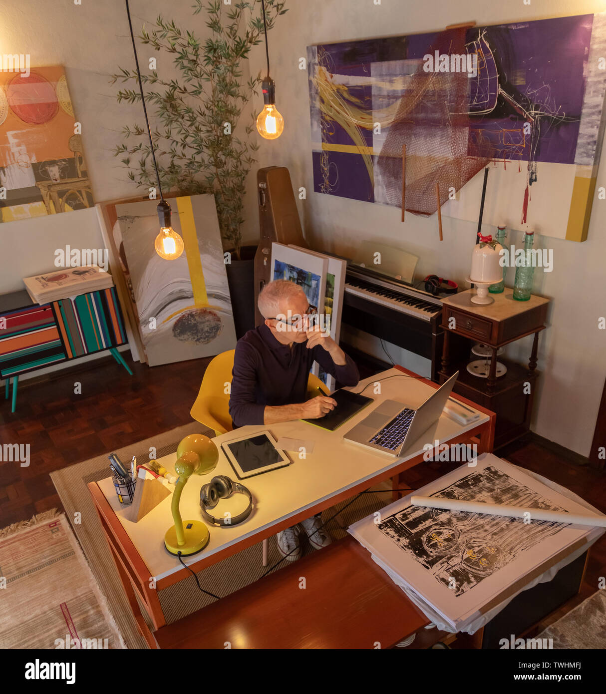 Middle aged man using computer in his art studio and drawing on his tablet Stock Photo