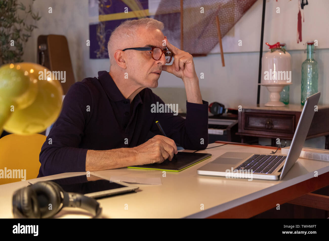 Middle aged man using computer in his art studio and drawing on his tablet Stock Photo
