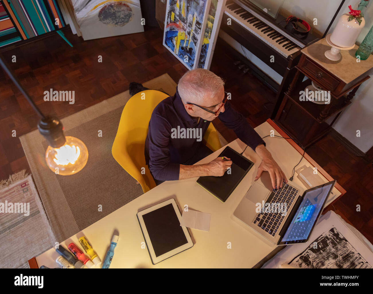 Middle aged man using computer in his art studio and drawing on his tablet Stock Photo