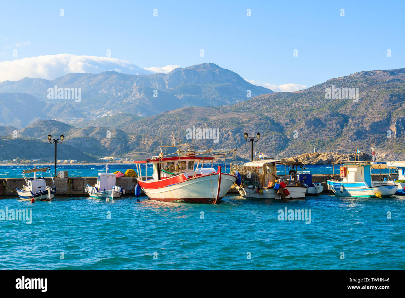 Fishing boats in picturesque Pigadia port on Karpathos island at sunset time, Greece Stock Photo