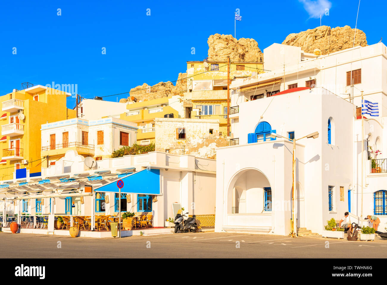 Whitewashed buildings in picturesque Pigadia port on Karpathos island at sunset time, Greece Stock Photo