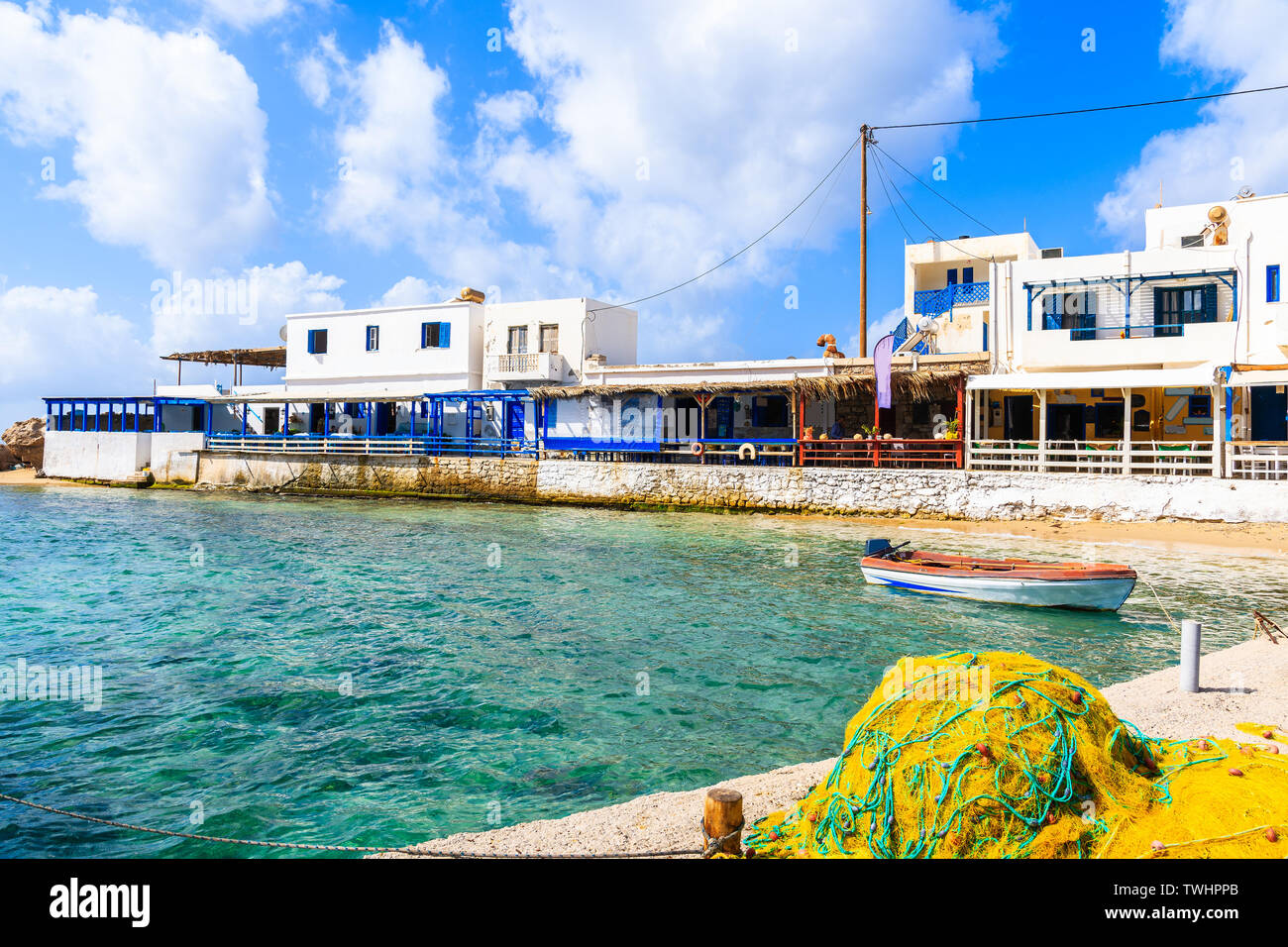 Fishing nets and boat in Lefkos port with typical Greek houses on shore, Karpathos island, Greece Stock Photo