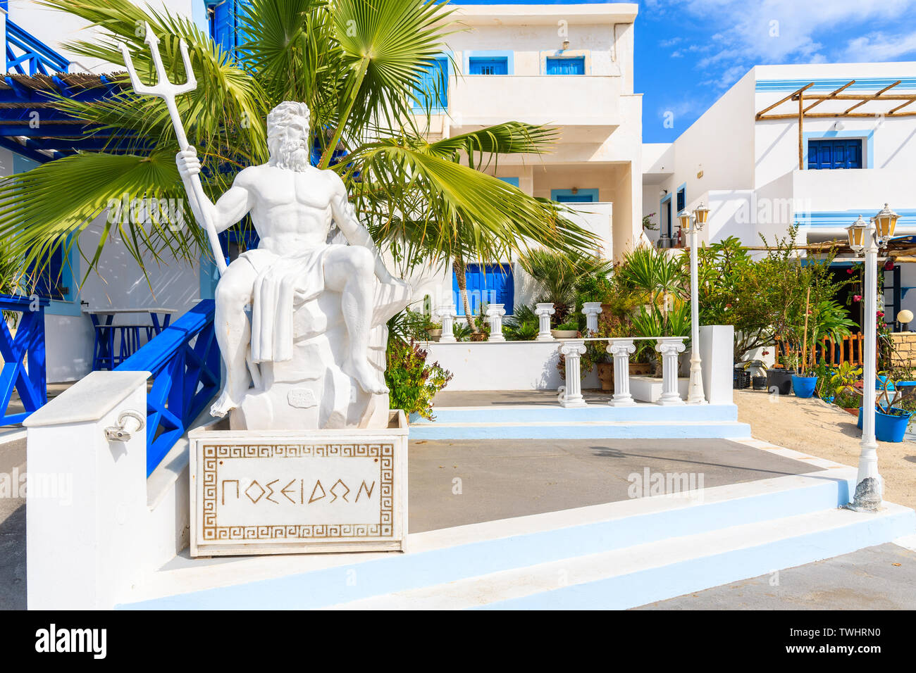 Sculpture of Poseidon, god of the sea in ancient Greek religion and myth in front of typical buildings in Finiki port, Karpathos island, Greece Stock Photo