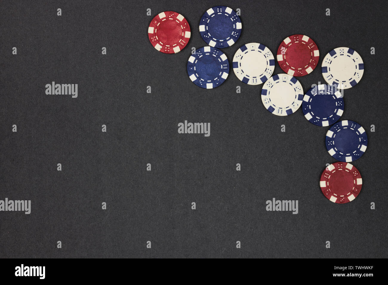 Red, white and blue poker chips on one corner. Dark copyspace