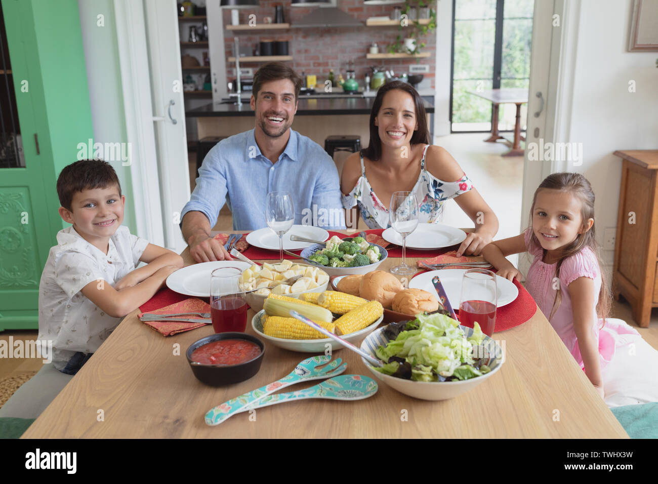 Family sitting together at dining table in comfortable home Stock Photo ...