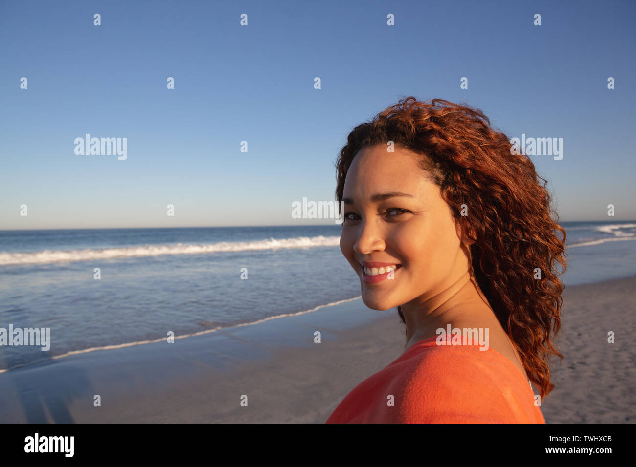 Beautiful happy woman looking at camera on beach in the sunshine Stock Photo