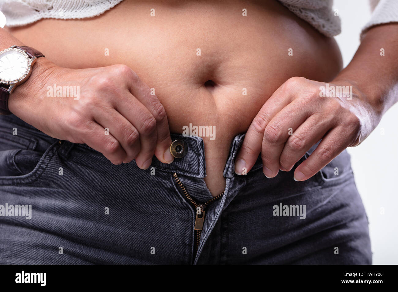 Close-up Of Woman Hands Unable To Close The Pants Due To Gaining Fat On Hips. Stock Photo