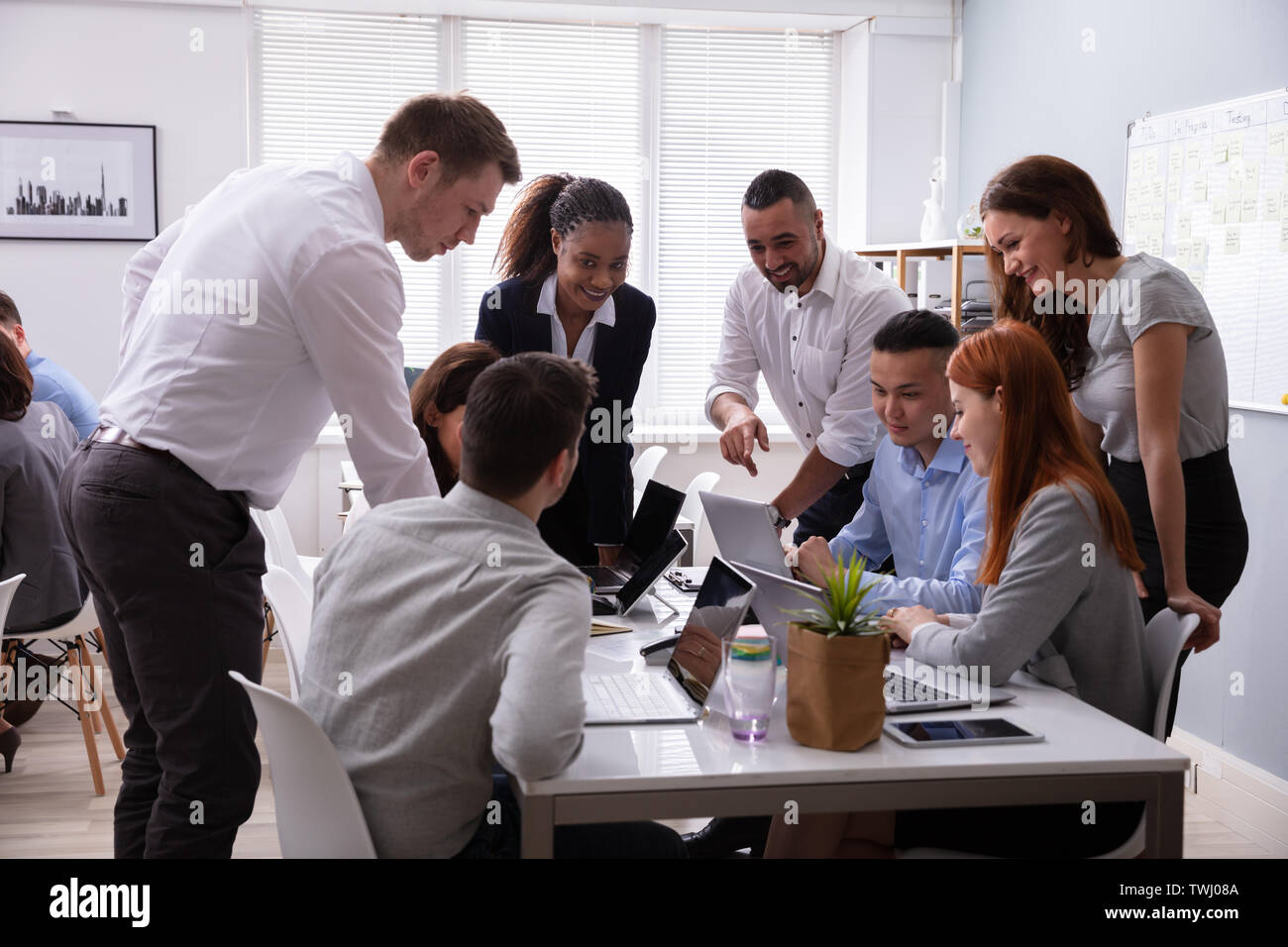 Group Of Young Diverse Business People Working And Communicating While Sitting At The Office Desk Stock Photo