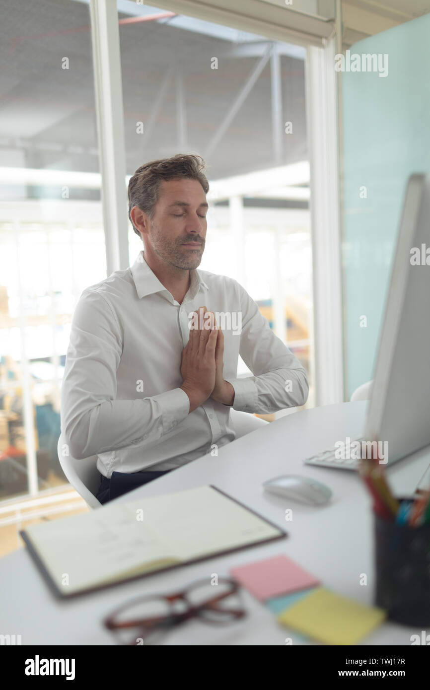 Business executive doing yoga at desk in a modern office Stock Photo ...