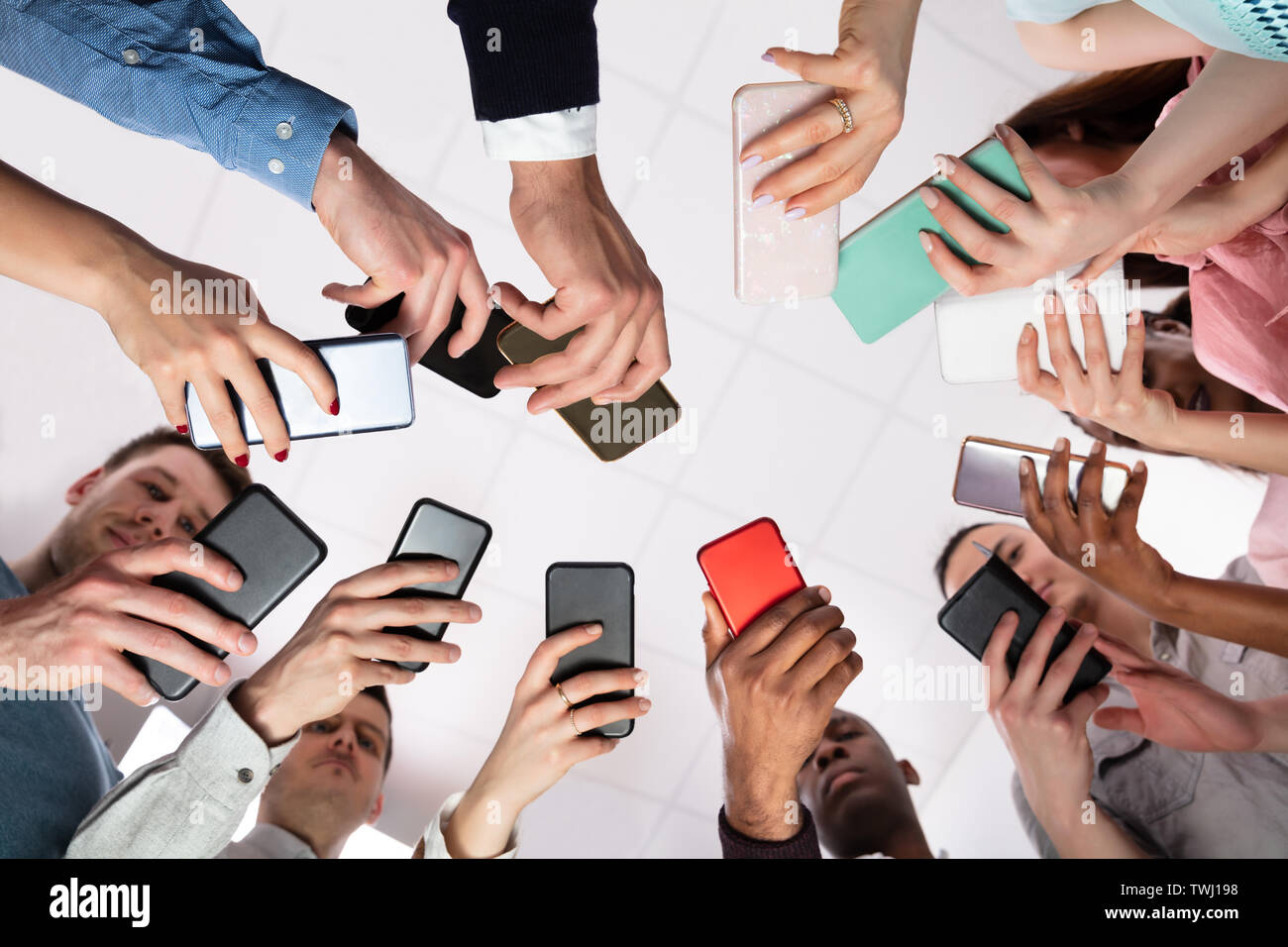 Group Of People Standing In Circle Using Smartphone Stock Photo