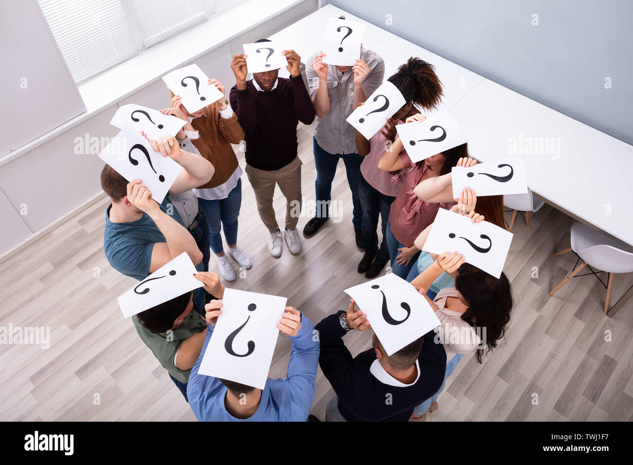 Group Of Multi-ethnic People Standing In Circle Holding Question Mark Sign Over Their Heads Stock Photo