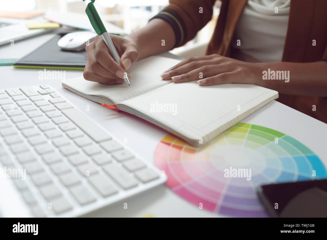 Female graphic designer writing on diary at desk in a modern office ...
