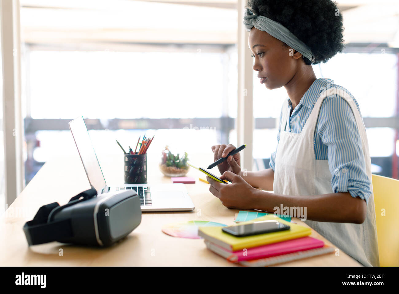 Female graphic designer using graphics tablet while looking at laptop at desk Stock Photo