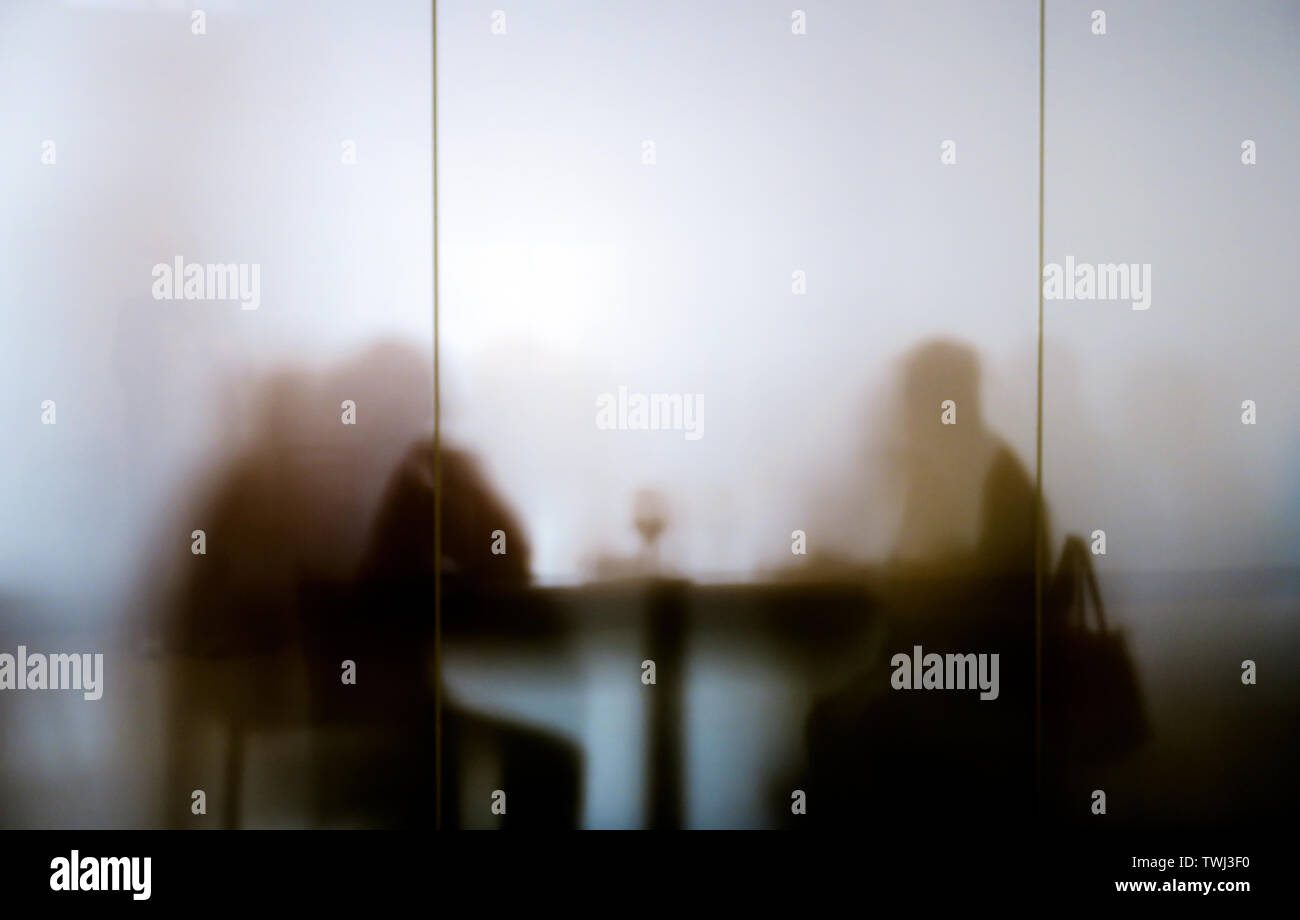 Silhouttes seated at table eating lunch Stock Photo