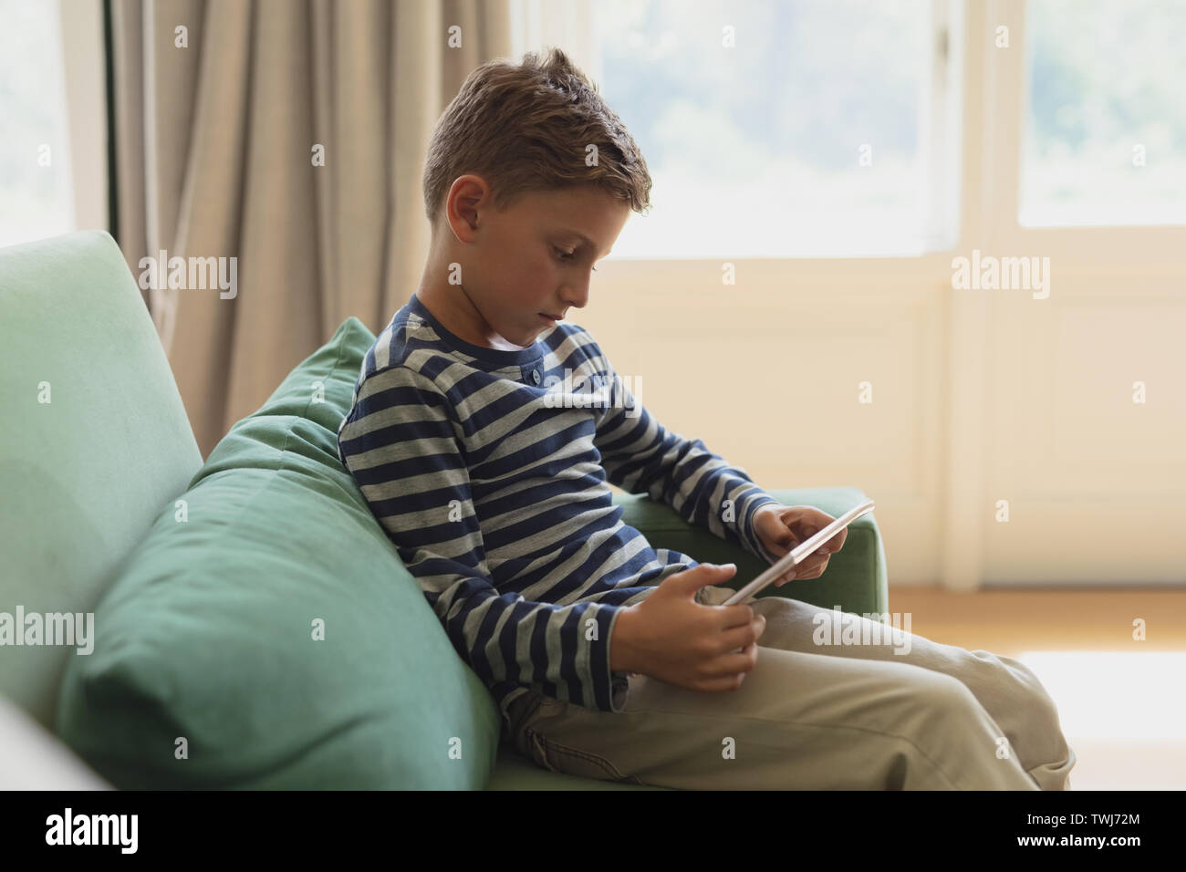 Boy using digital tablet on sofa in a comfortable home Stock Photo