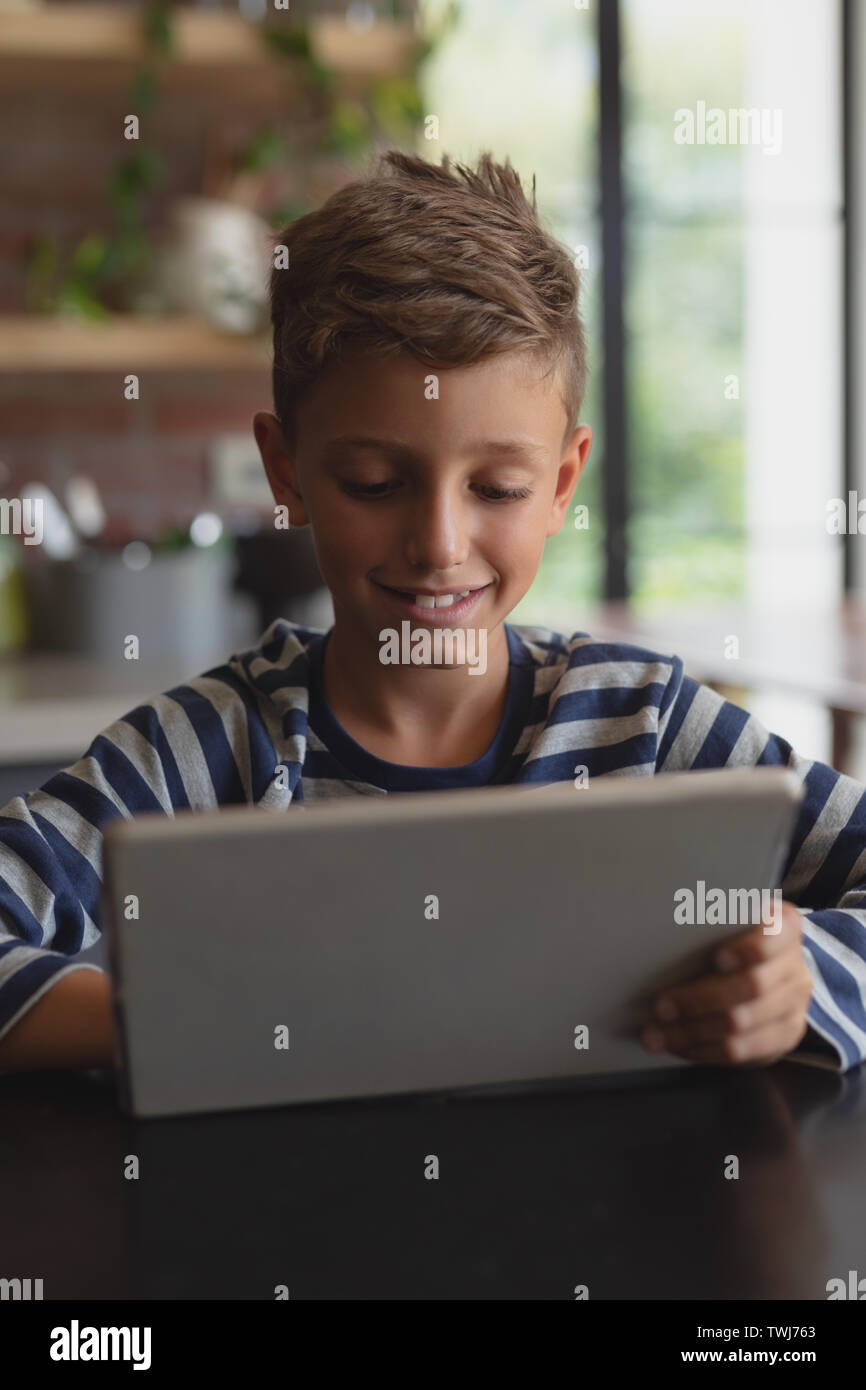 Boy using digital tablet at table in kitchen at home Stock Photo
