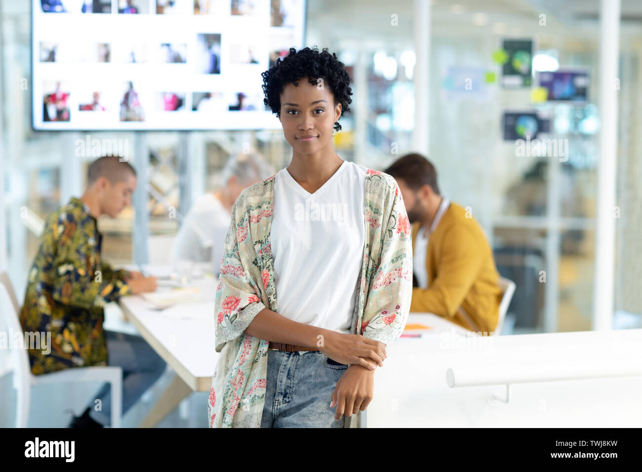Female fashion designer leaning on a table at conference room in office ...