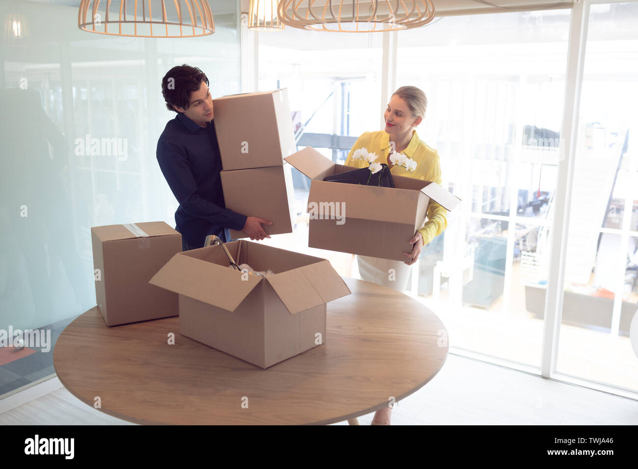 Male and female executives holding cardboard boxes in office Stock Photo Alamy