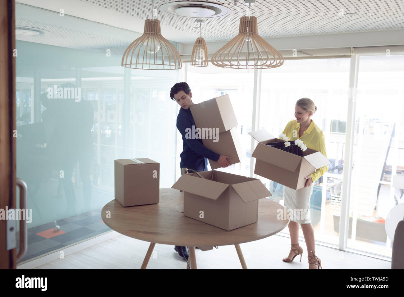 Male and female executives holding cardboard boxes in office Stock Photo