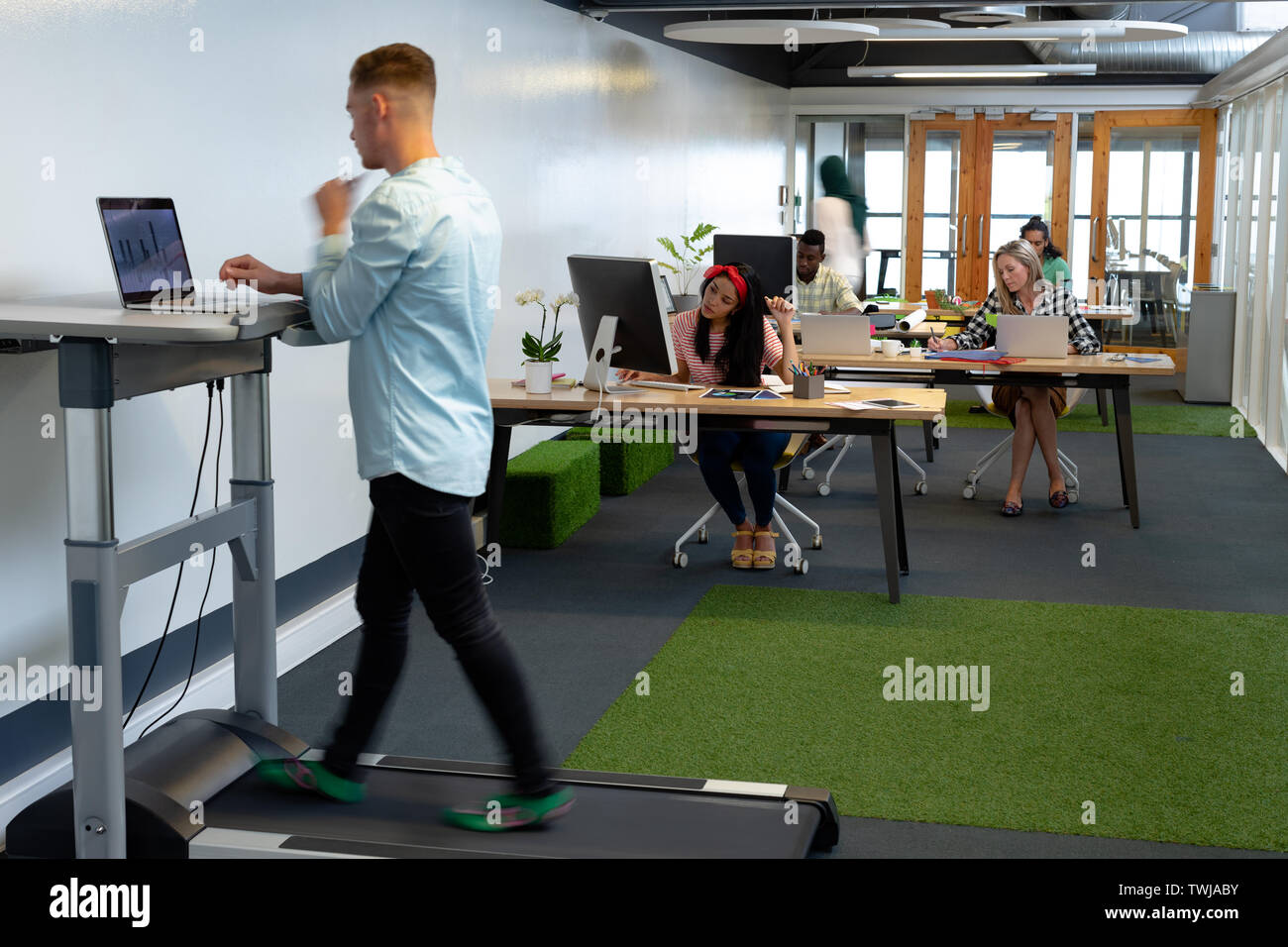 Businessman working on laptop while exercising on treadmill in a modern office Stock Photo Alamy