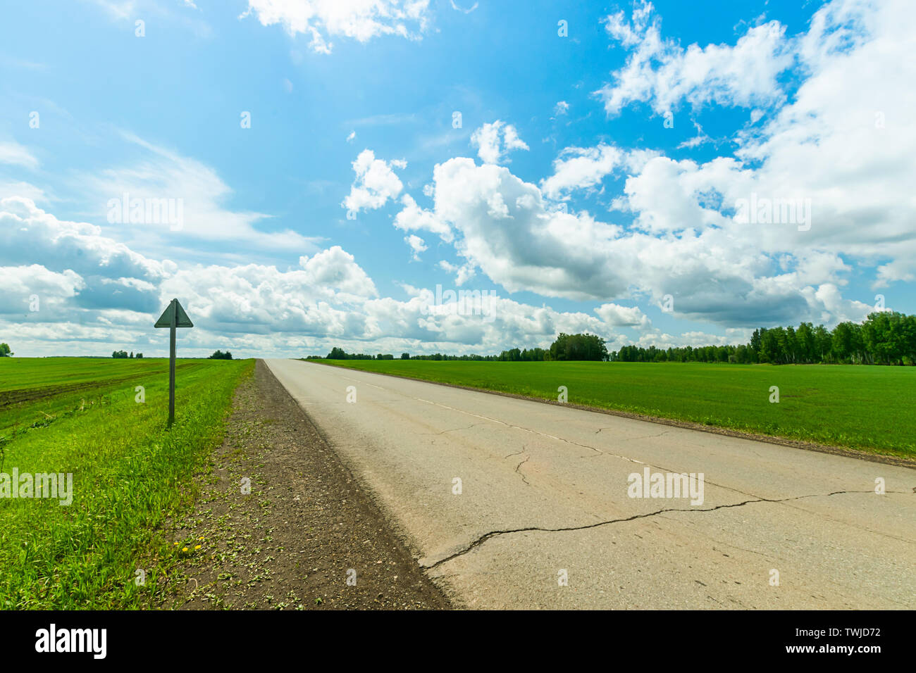 Straight road stretching into the horizon and bright blue sky in the ...